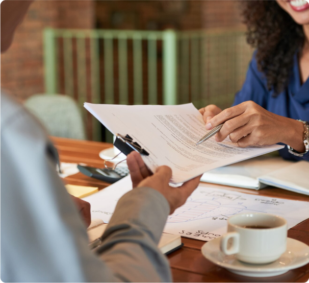 una mujer y un hombre firmando un contrato en una mesa.